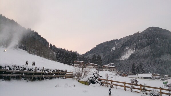 Une région montagneuse enneigée, avec des chalets en bois et une clôture en bois.