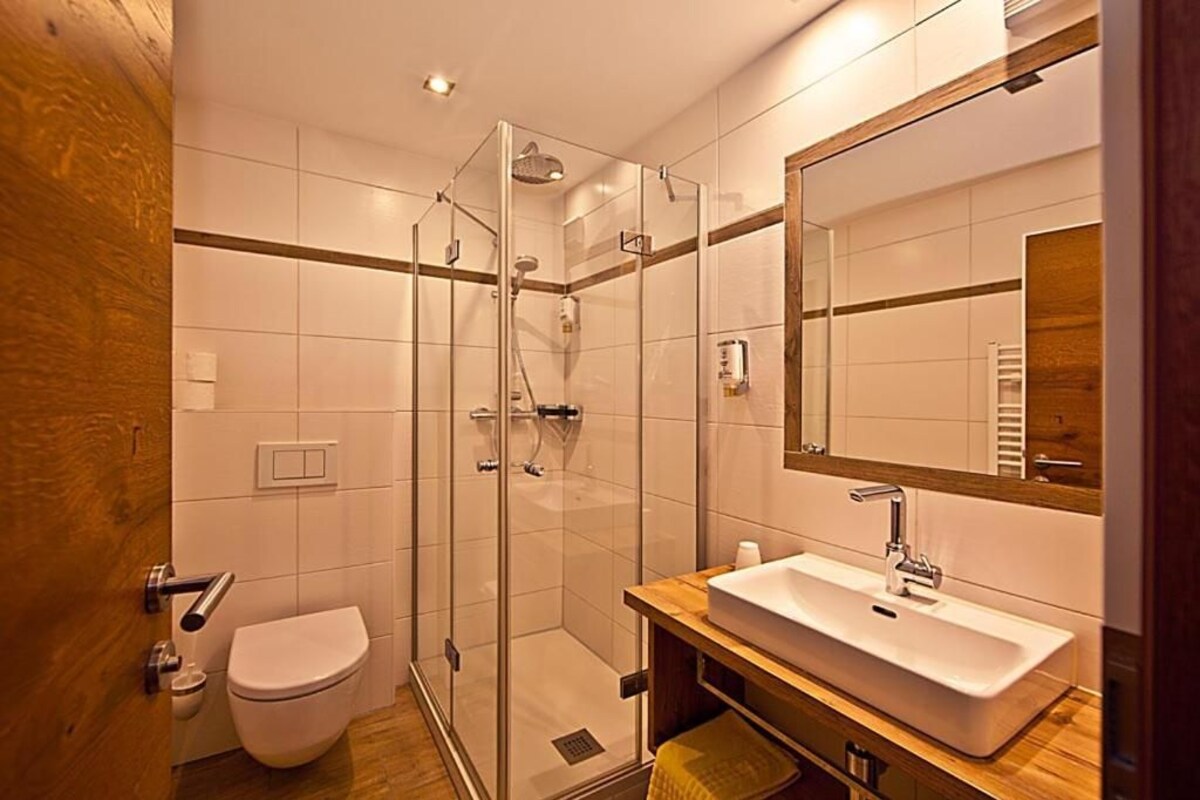 Une salle de bain moderne avec une douche à parois de verre, un lavabo blanc et un meuble-lavabo en bois.