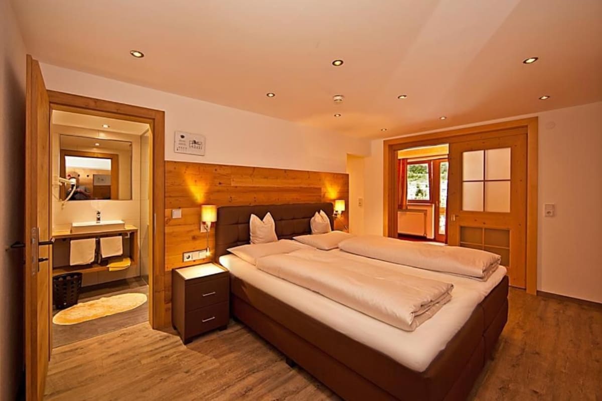 A bedroom with a large bed, bedside tables, a mirror, and a wooden headboard.
