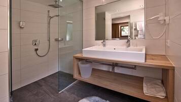 A modern bathroom with a glass-enclosed shower, a large mirror, and a wooden vanity.