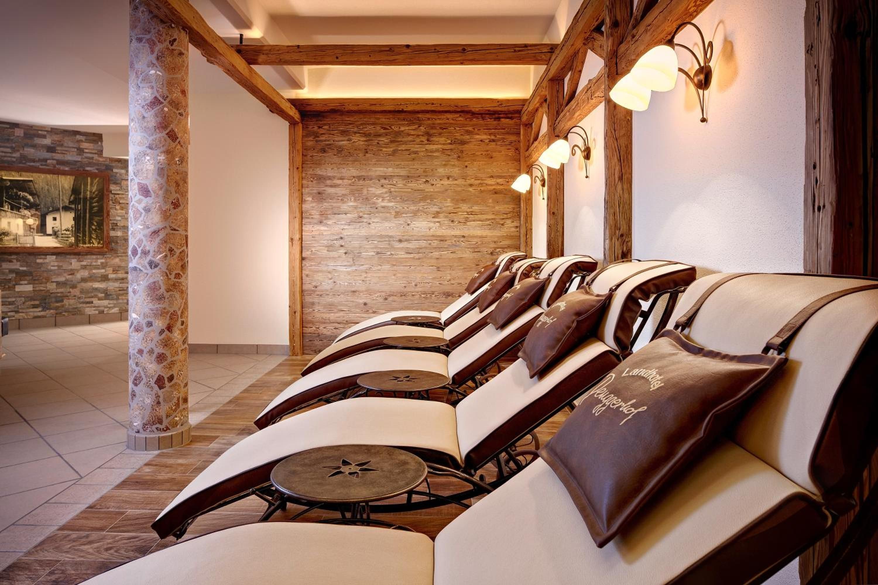 A row of leather chairs with attached cushions, wooden beams, and a stone wall in the background.