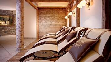 A row of leather chairs with attached cushions, wooden beams, and a stone wall in the background.