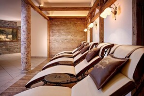 Una hilera de sillones de cuero con cojines incorporados, vigas de madera y una pared de piedra al fondo.