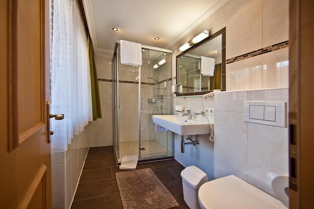 Une salle de bain moderne avec une douche à parois de verre, un lavabo blanc et des toilettes.