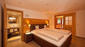 A bedroom with a large bed, bedside tables, a mirror, and a wooden headboard.