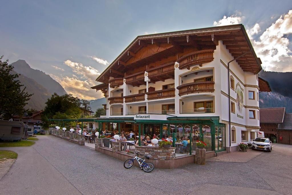 A restaurant with outdoor seating, a bicycle parked in front, and mountains in the background.