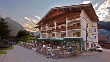 A restaurant with outdoor seating, a bicycle parked in front, and mountains in the background.