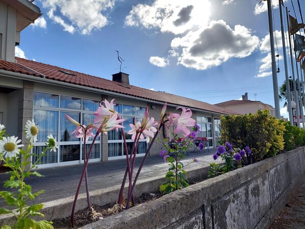 A building with large windows, a red-tiled roof, and a concrete retaining wall with flowers. - Estalagem Cruz Da Mata (Mangualde)