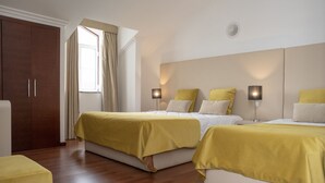 Een hotelkamer met twee bedden, een kledingkast, een raam met gordijnen en bedlampjes.