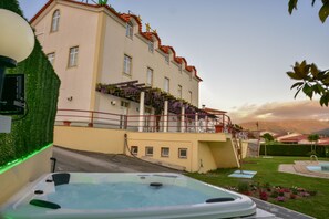 Um edifício com piscina, banheira de hidromassagem e escadaria que dá para uma varanda com plantas.