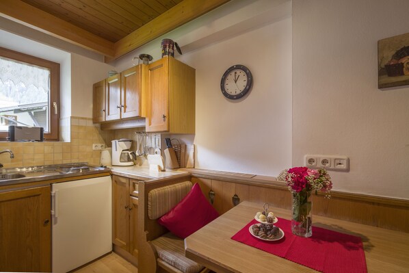 A kitchen with wooden cabinets, a sink, a coffee maker, and a clock on the wall. - Landhaus Gasser (Mayrhofen)