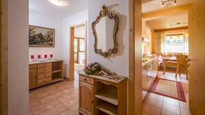 A kitchen with wooden cabinets, a mirror, and a dining area with a table and chairs. - Landhaus Gasser (Mayrhofen)