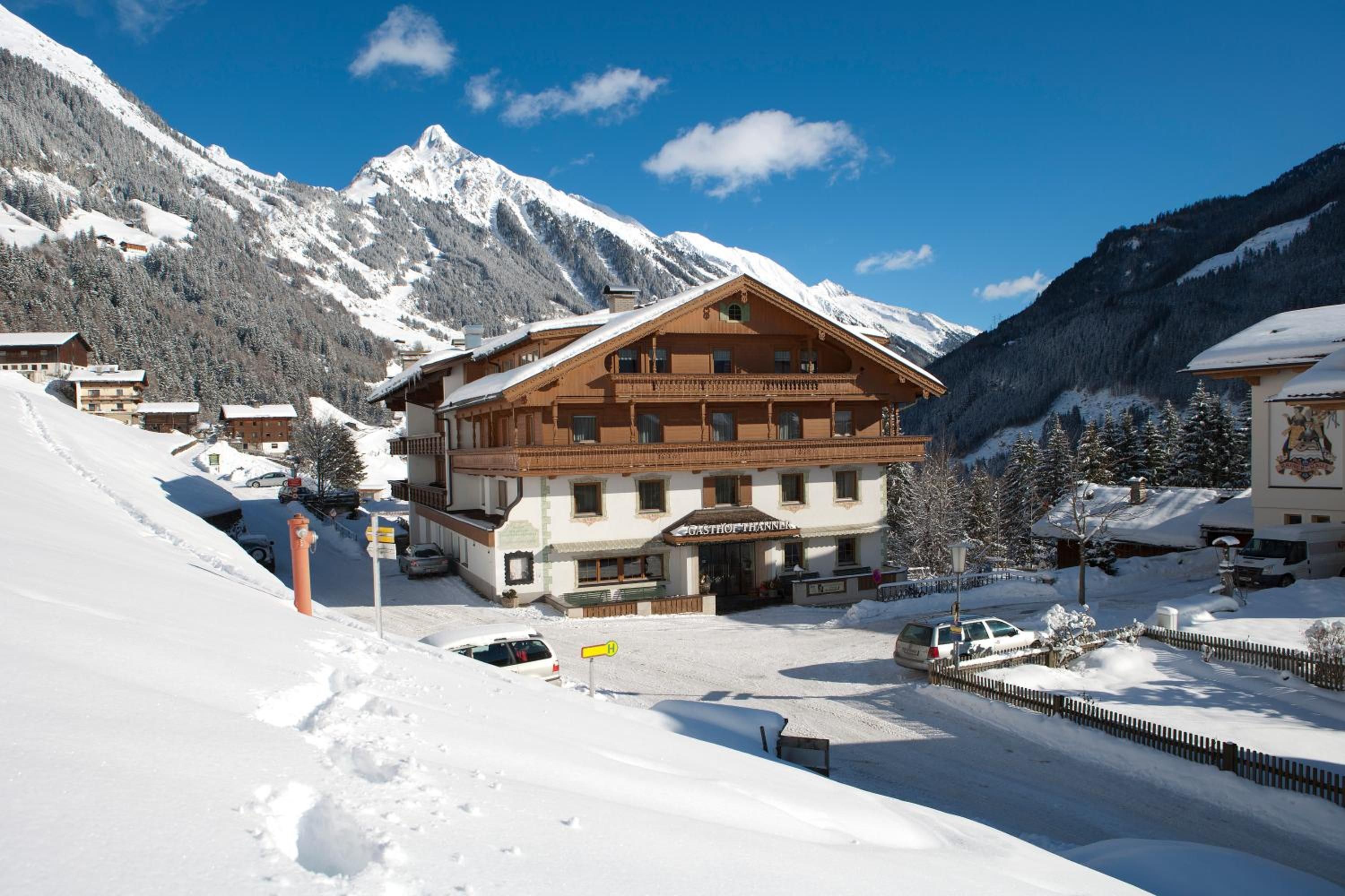 Um refúgio de montanha com fachada de madeira, um restaurante e vista para montanhas cobertas de neve.