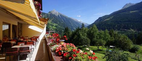 A restaurant with outdoor seating overlooking a mountainous landscape.