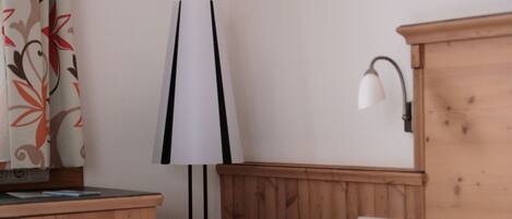 A corner of a room with a wooden cabinet, a lamp, and a wall-mounted light fixture.