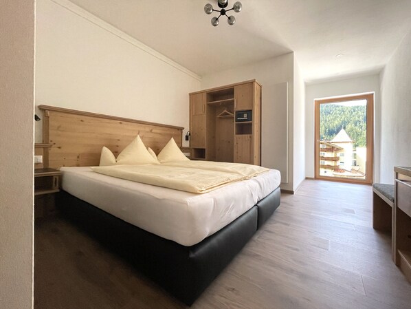 A bedroom with a large bed, wooden headboard, and a wardrobe. - Glück auf (Mayrhofen)