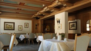 A dining area with wooden tables and chairs, framed pictures on the walls, and a wooden ceiling with exposed beams. - Glück auf (Mayrhofen)