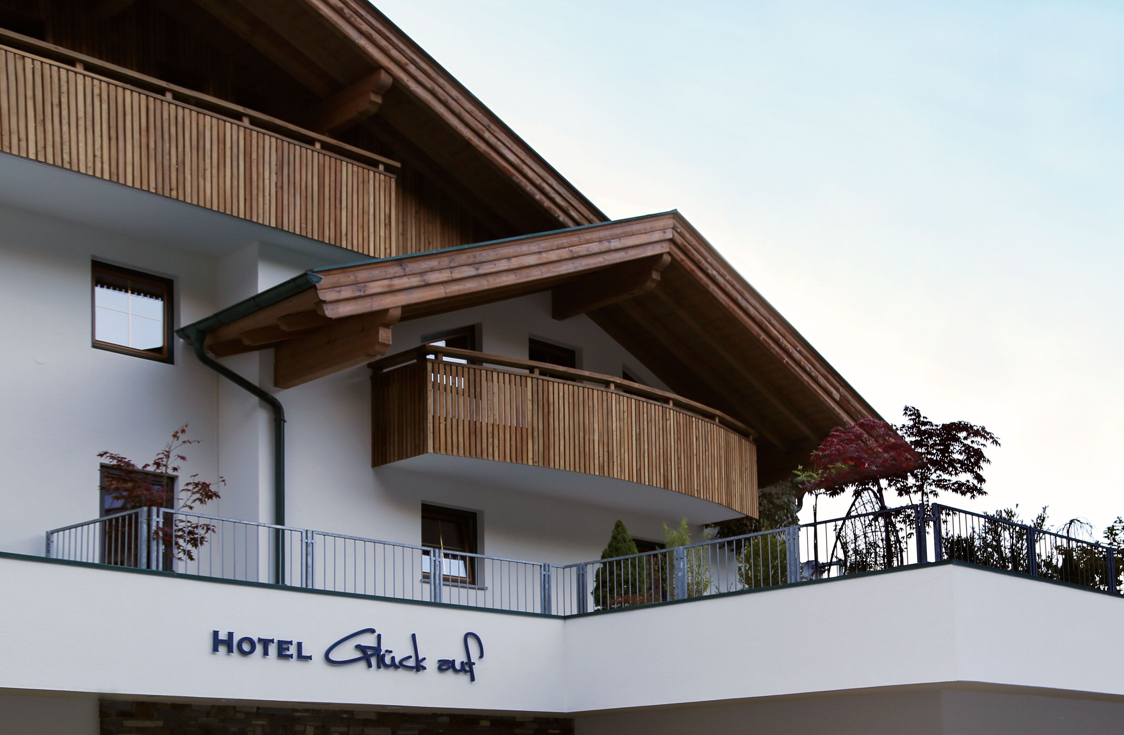 A hotel with a balcony, wooden railings, and a sign that reads "HOTEL Glickauf".