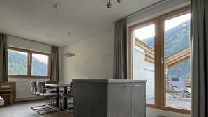 A modern kitchen with a dining area, large windows, and a view of a mountainous landscape. - Glück auf (Mayrhofen)
