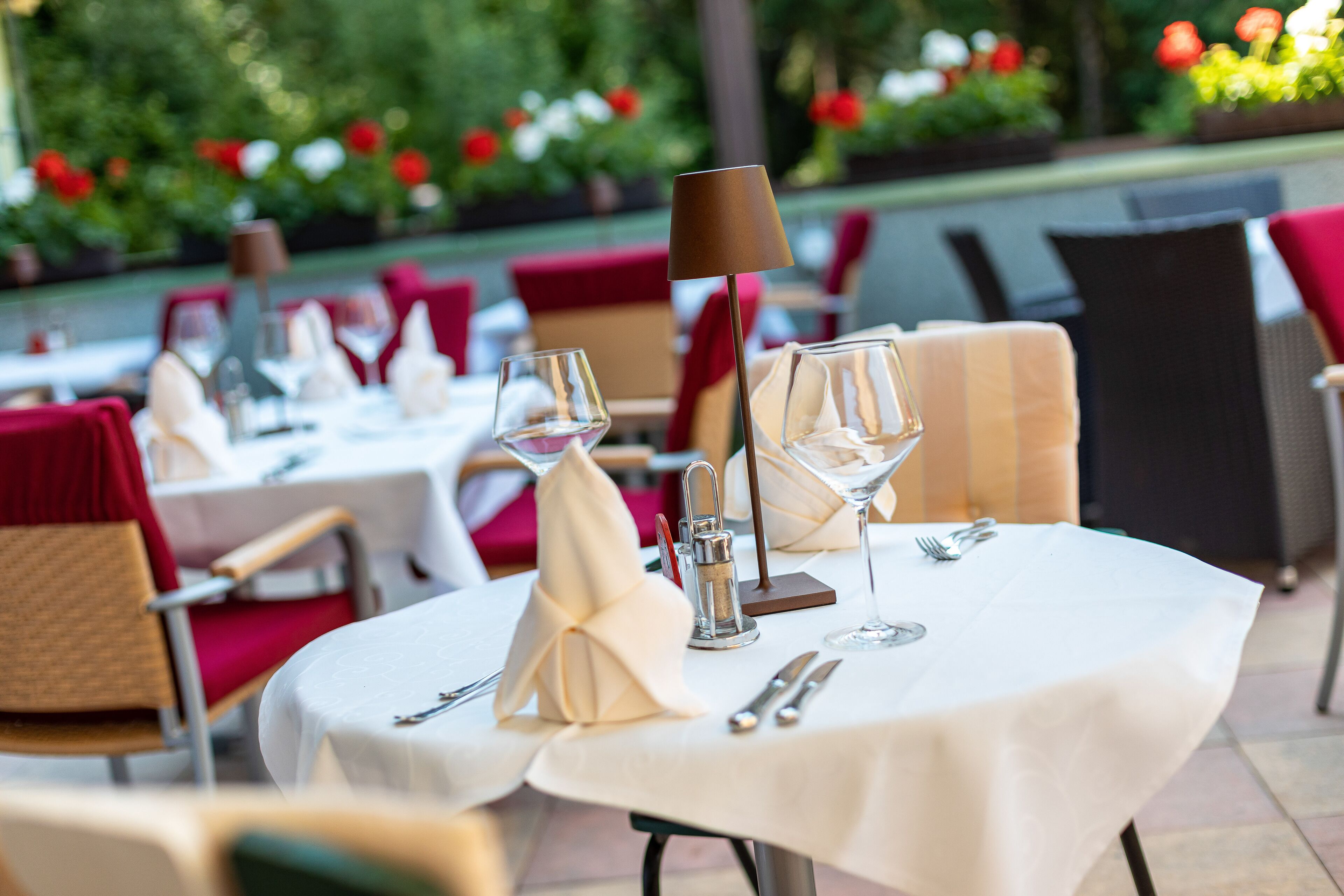 Un ambiente de restaurante con mesas dispuestas para comer, incluyendo copas de vino, cubiertos y servilletas.