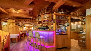 A wooden interior with a bar area, bar stools, and a wooden ceiling. - Ländenhof (Mayrhofen)