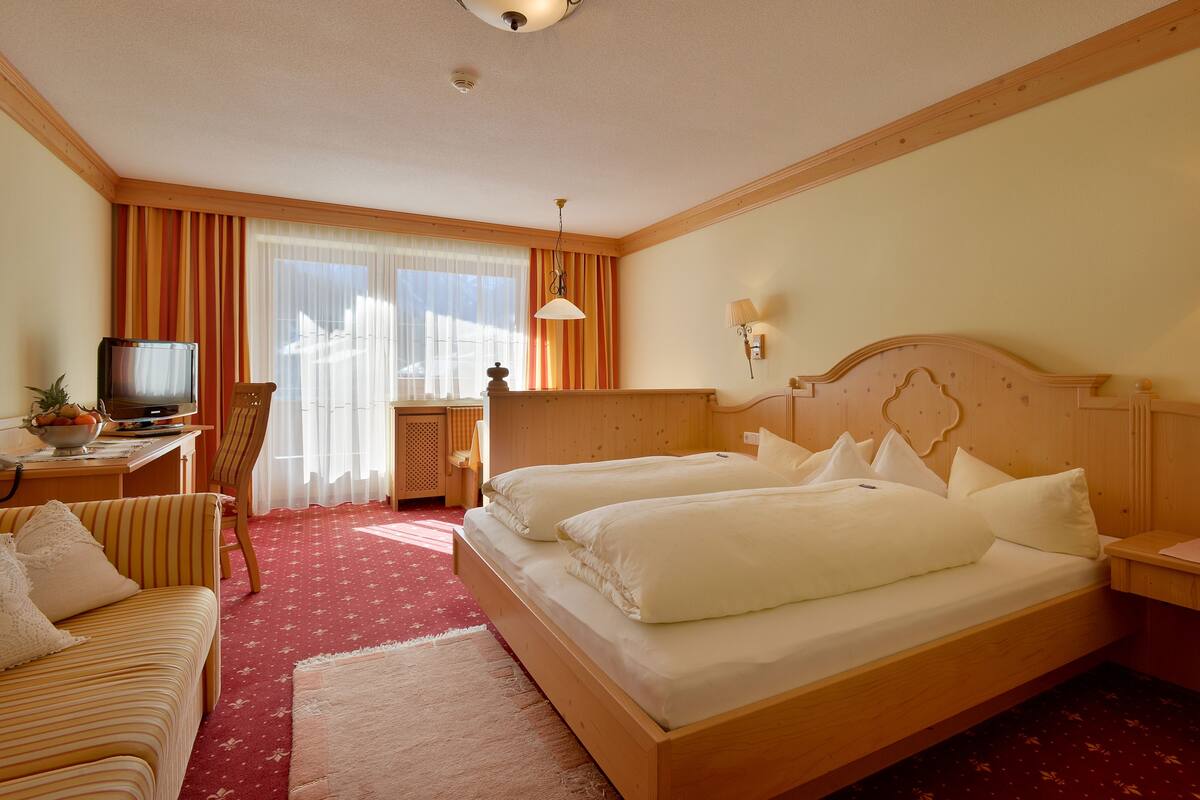 Quarto de hotel com duas camas, televisão, escrivaninha e uma cadeira.