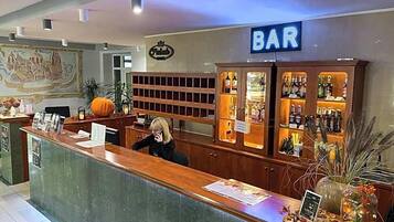 A bar area with a reception desk, a sign indicating the bar, and shelves with bottles.
