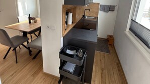 A compact kitchen with a wooden countertop, a sink, and a small dining area with a table and chairs. - Haus Alpina (Schladming)