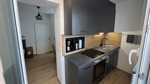 A modern kitchen with dark cabinets, a built-in stove, and a wooden backsplash. - Haus Alpina (Schladming)