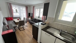 A compact living space with a kitchenette, dining area, and seating area. - Haus Alpina (Schladming)