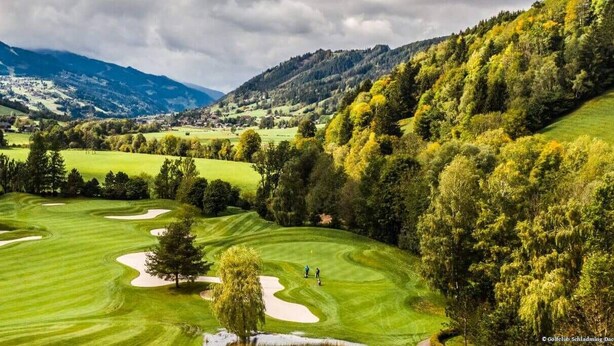 A golf course with rolling hills, trees, and a mountainous backdrop. - Haus Alpina (Schladming)