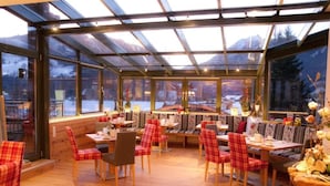 Un restaurante con techo de vidrio, piso de madera y sillas rojas con estampado de cuadros.