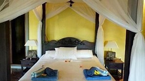 Una cama con dosel, dos mesitas de noche y un buró.