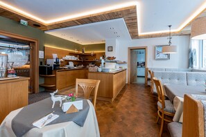 A restaurant with a wooden interior, a bar area, and a seating arrangement with tables and chairs. - Hotel Garni Entstrasser (Kitzbühel)