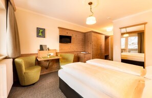 A hotel room with a bed, a desk, a chair, a television, and a window. - Hotel Garni Entstrasser (Kitzbühel)