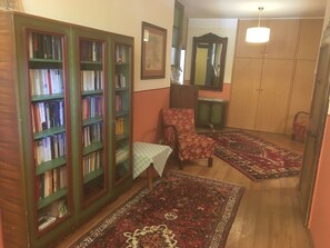 Una habitación con una estantería, una silla, una mesa, un espejo y una alfombra estampada.