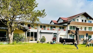 A two-story building with a balcony, a garage, and a tree in the foreground. - Tanneneck (Löffingen)