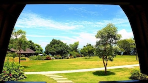 Vista da un balcone con un sentiero in pietra che conduce a una zona erbosa con alberi e un edificio sullo sfondo.