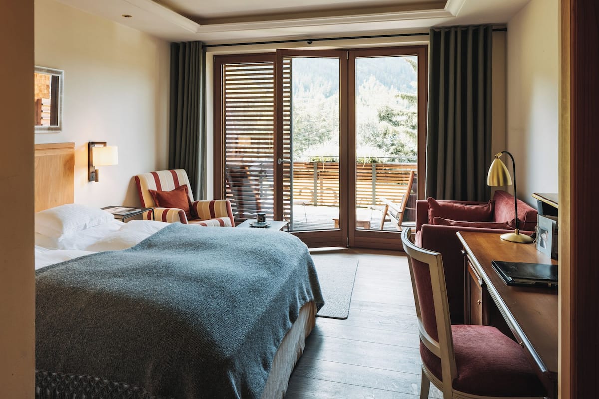 Une chambre d’hôtel dotée d’un grand lit, d’un bureau avec une chaise, d’un canapé et d’un balcon offrant une vue sur l’extérieur.