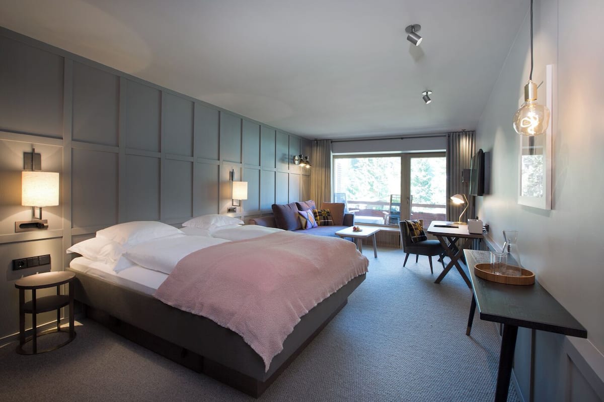 Une chambre d’hôtel moderne dotée d’un grand lit, d’un bureau et d’un balcon.