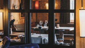 A cozy restaurant with wooden interiors, tables set for dining, and a blue sofa in the foreground. - Der Berghof (Lech am Arlberg)