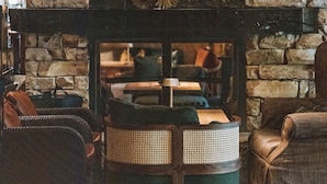A cozy living room with a stone fireplace, a woven coffee table, and comfortable seating. - Der Berghof (Lech am Arlberg)