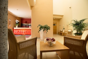 A reception area with wicker furniture, a reception desk, and a wall-mounted sign.