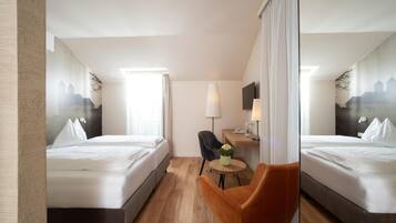 A hotel room with two beds, a small table, a chair, a lamp, and a TV.