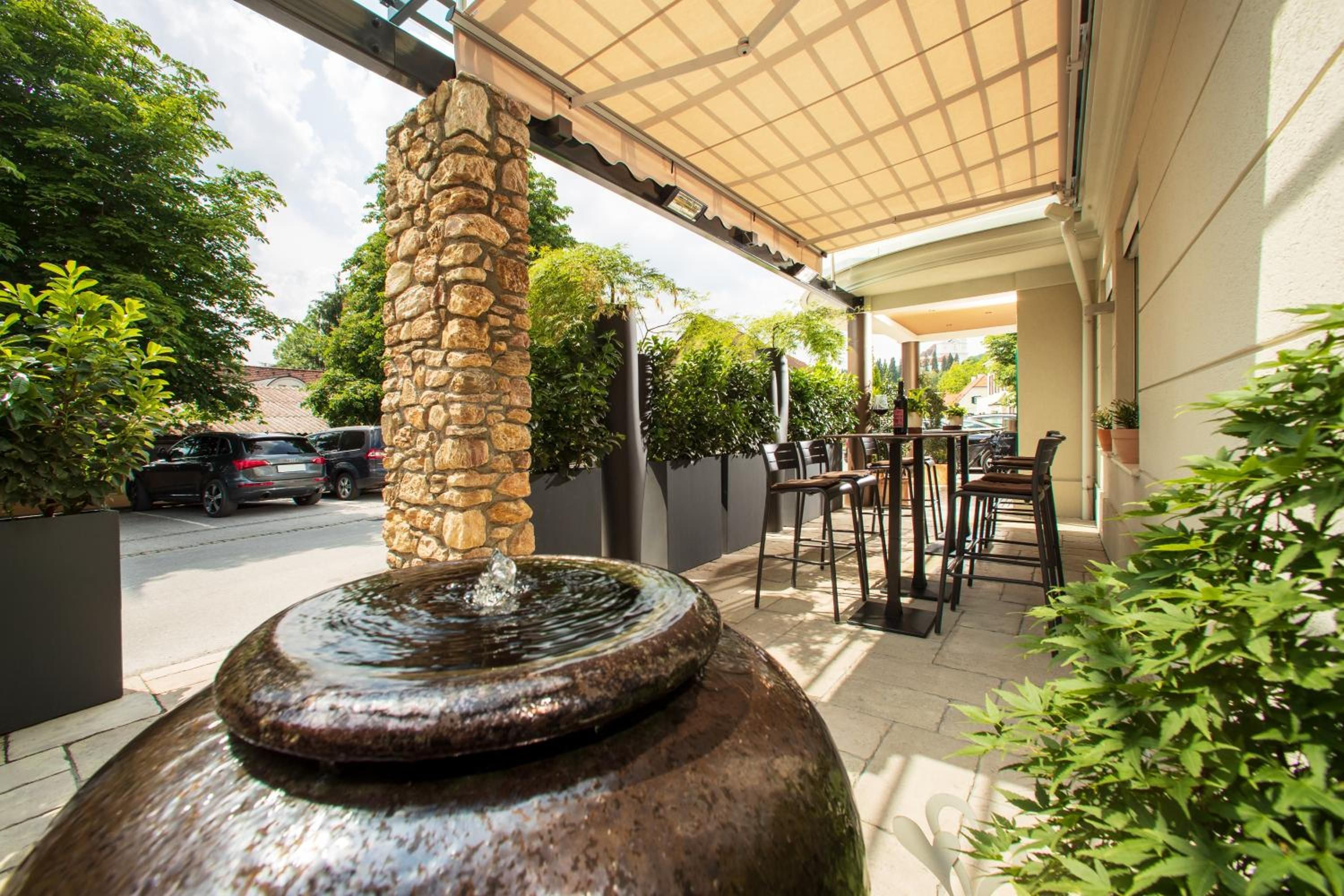 An outdoor patio area with a stone pillar, a water feature, and outdoor seating.