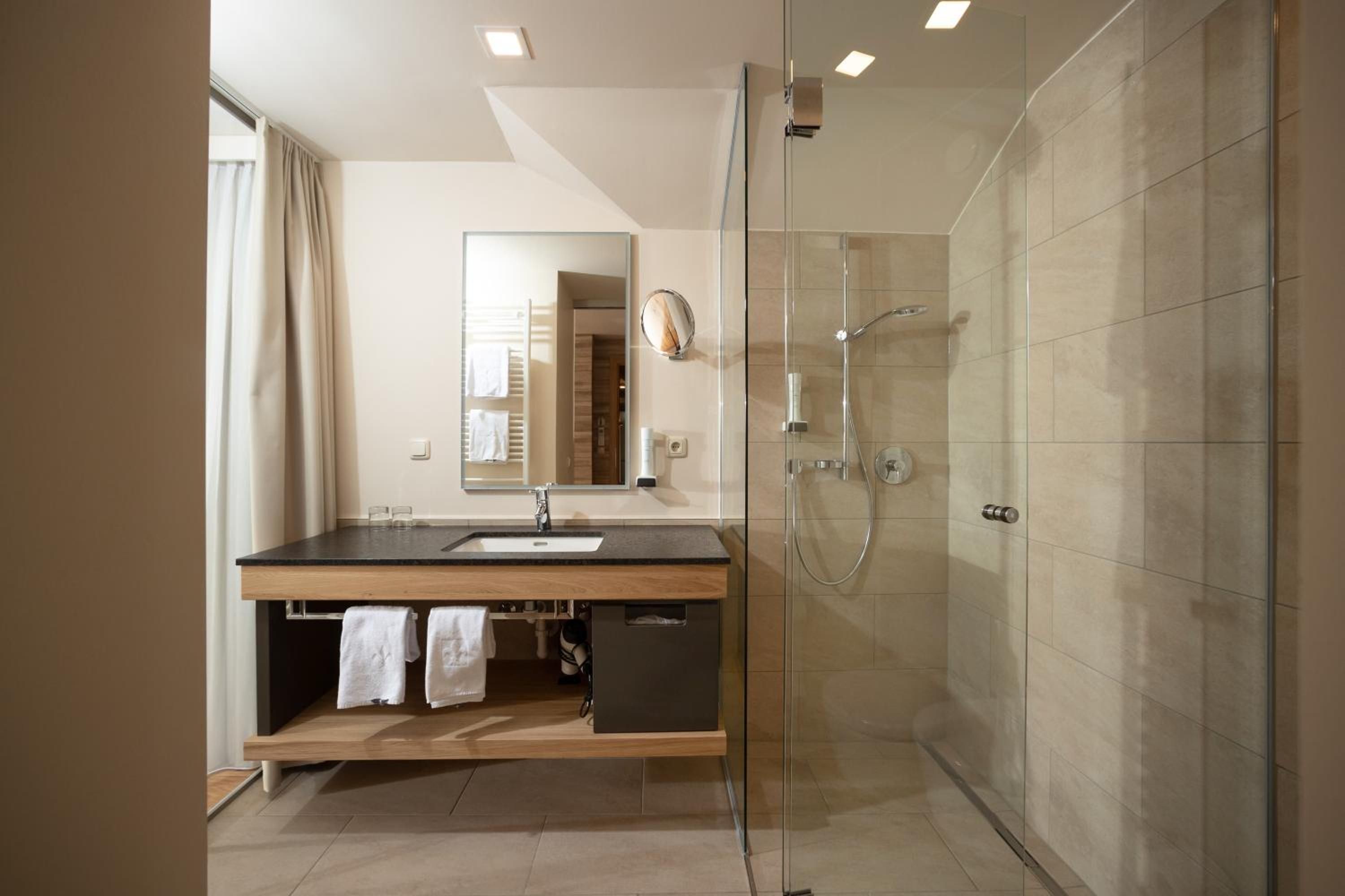 Ein modernes Badezimmer mit einer Duschkabine aus Glas, einem Holzbadezimmer-Möbel und einem großen Spiegel.