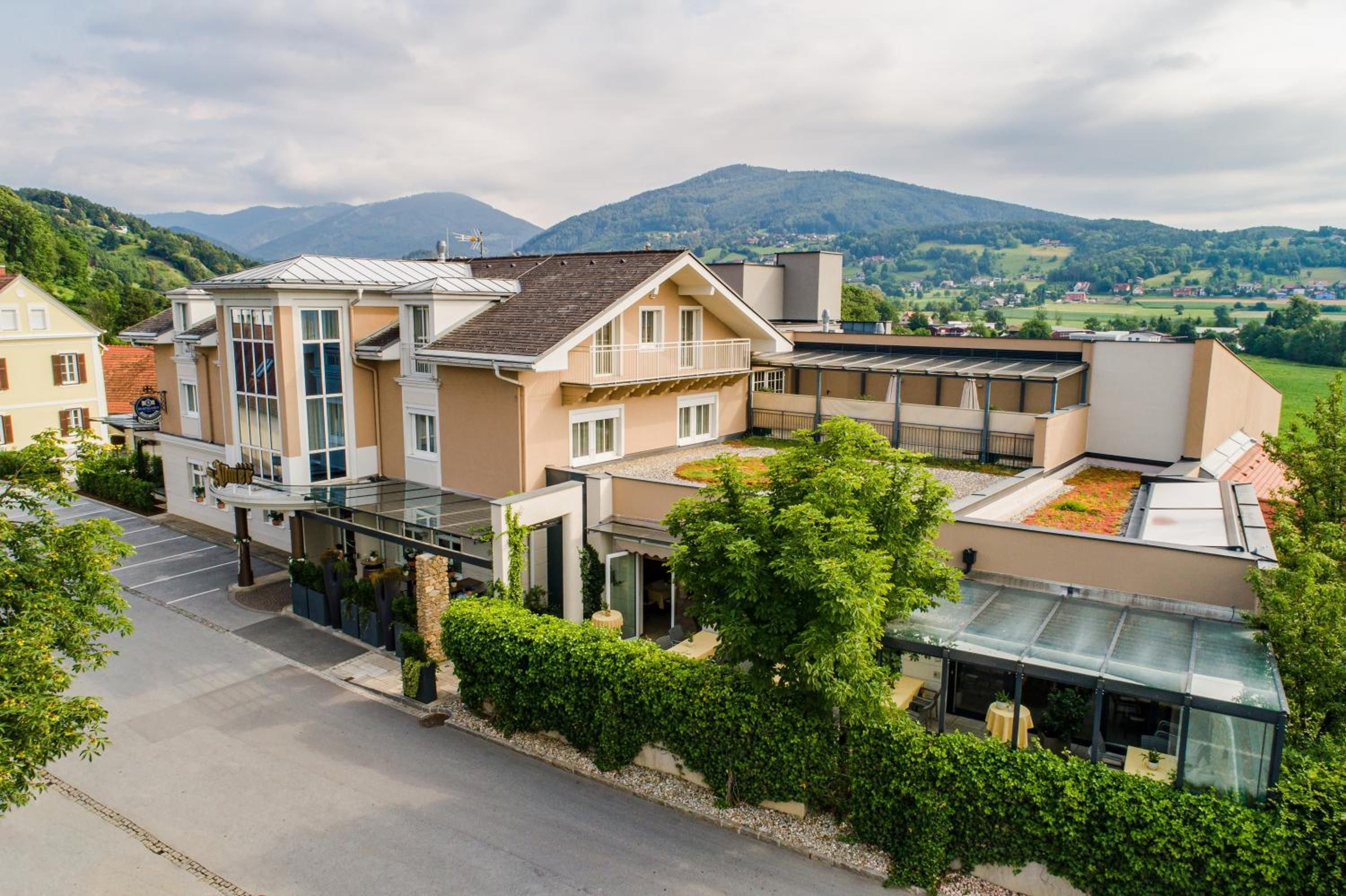 Ein modernes Hotel mit Glasfassade, mehreren Balkonen und Blick auf die umliegenden Hügel.