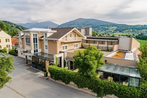 A modern hotel with a glass facade, multiple balconies, and a view of the surrounding hills.