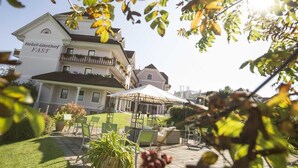 A hotel with a large outdoor patio area, a covered seating area, and a well-maintained lawn. - Mein Hotel Fast (Wenigzell)