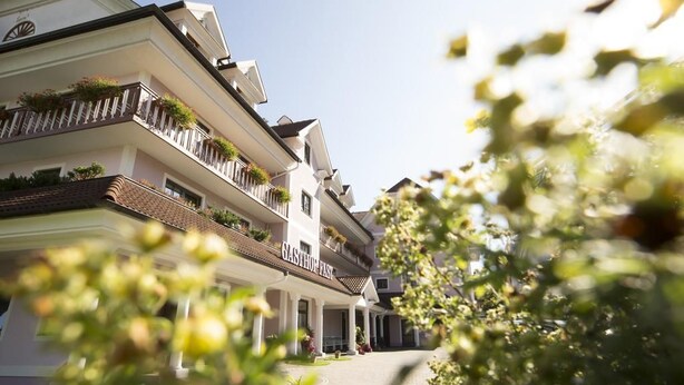 Un hotel de varios pisos con balcones, una entrada cubierta y un cielo despejado.